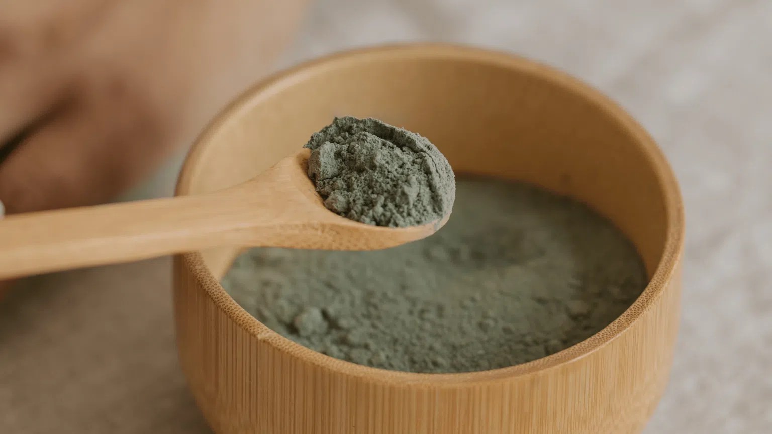 Zoom sur la poudre d'argile verte dans un pot en bambou pour lutter contre la sensation de jambes lourdes